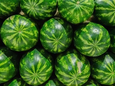 Close-up of fresh green watermelons stacked in vibrant arrangement, perfect for summer themes.